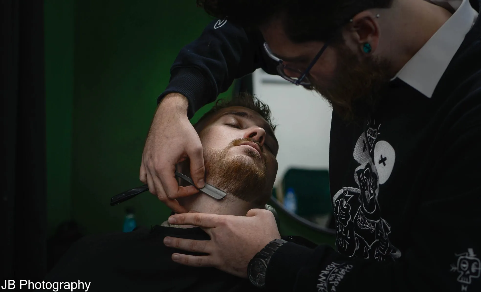 Man shaving customer beard